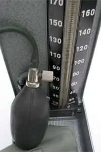 Close up of a black oxygen cylinder with a hose attached to it, sitting on a stand