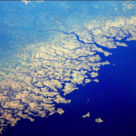 Ocean from an airplane window, with the sky filled with clouds and the water below